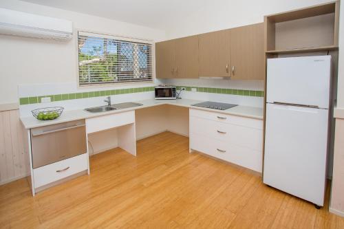 a kitchen with white cabinets and a white refrigerator at BIG4 Park Beach Holiday Park in Coffs Harbour