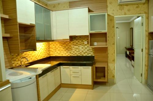 a small kitchen with white cabinets and a sink at MTC Mega Mas Apartment in Manado