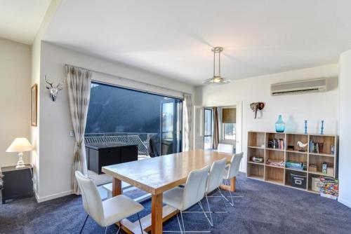 a dining room with a table and white chairs at The Queenstown Bothy in Queenstown