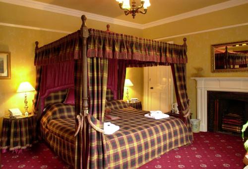 a bedroom with a canopy bed and a fireplace at Atholl Arms in Blair Atholl