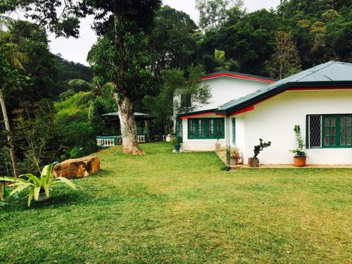 a white house with a tree in the yard at Ella Escapade Hostel in Ella