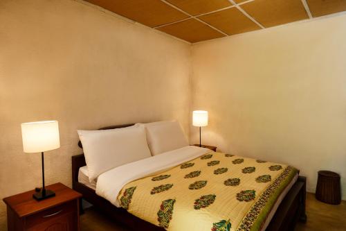 a bedroom with a bed with two lamps on it at Meena Amma's Tea Experience in Ambawela