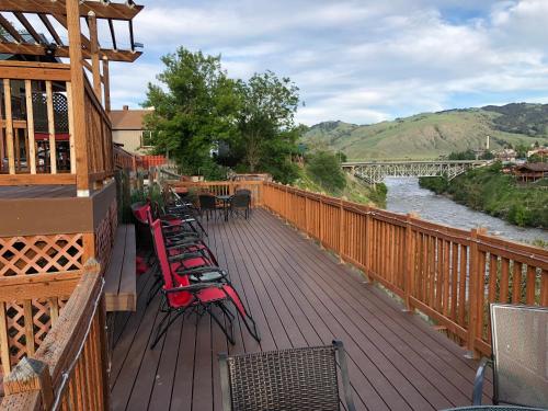 eine Terrasse mit Stühlen, Tischen und einem Fluss in der Unterkunft Yellowstone Riverside Cottages in Gardiner