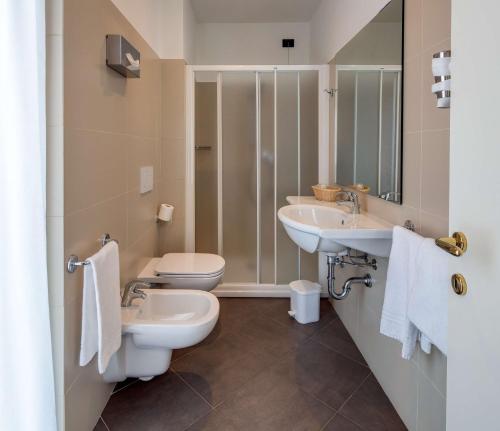 een badkamer met 2 wastafels en een toilet bij Best Western Hotel Nuovo in Garlate