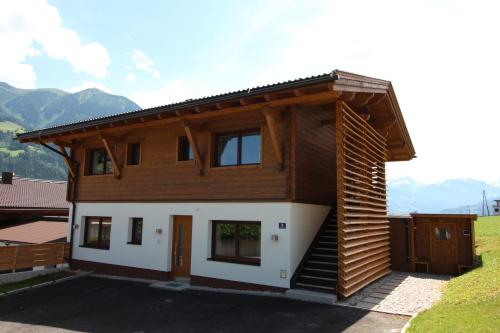 a house with a wooden facade with mountains in the background at Chalet Fügen in Fügen