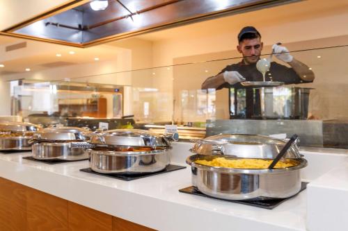a chef in a kitchen preparing food in pots at Best Western Plus Hotel Plaza in Rhodes Town