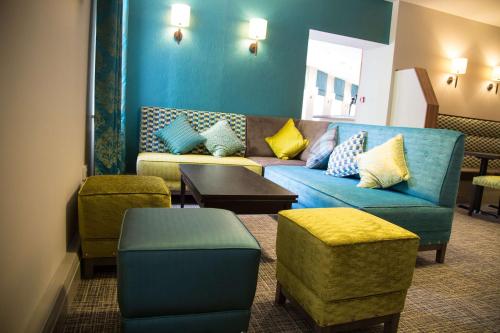 a living room with a blue couch and chairs at Best Western Plus Ullesthorpe Court Hotel & Golf Club in Lutterworth