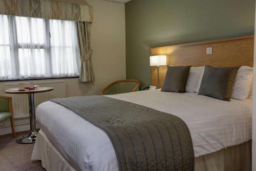 a hotel room with a large bed and a table at Best Western Plus Ullesthorpe Court Hotel & Golf Club in Lutterworth