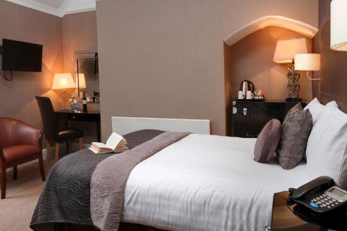 a hotel room with a bed with a book on it at Glendower Hotel BW Signature Collection in Lytham St Annes