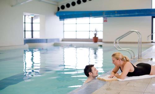 mężczyzna i kobieta w basenie w obiekcie Best Western Plus White Horse Hotel w mieście Londonderry/Derry