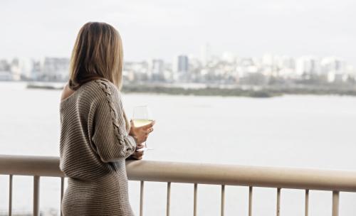 卡倫德拉的住宿－雙子座度假酒店，站在一个眺望着水面的阳台上的女人