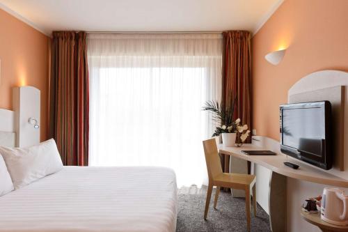 a hotel room with a bed and a desk with a television at Best Western Astoria in Juan-les-Pins