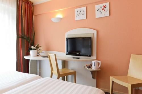 a hotel room with a bed and a desk with a tv at Best Western Astoria in Juan-les-Pins