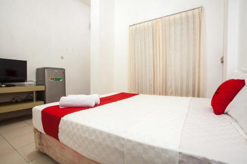 Schlafzimmer mit einem großen weißen Bett mit roten Akzenten in der Unterkunft RedDoorz near Taman Bungkul in Surabaya