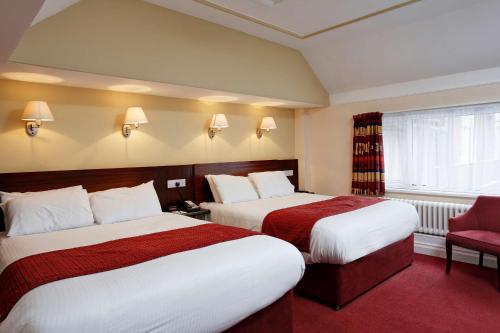 a hotel room with two beds and a red chair at Belvilla Crewe Arms Hotel in Crewe
