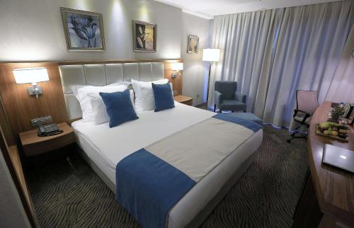 a hotel room with a large bed with blue pillows at Best Western Premier Karsiyaka Convention & Spa Hotel in Izmir