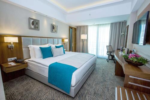 a hotel room with a large bed and a desk at Best Western Premier Karsiyaka Convention & Spa Hotel in Izmir