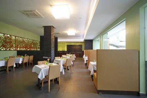 a dining room with white tables and chairs and a podium at Best Western Premier Garden Hotel Entebbe in Entebbe