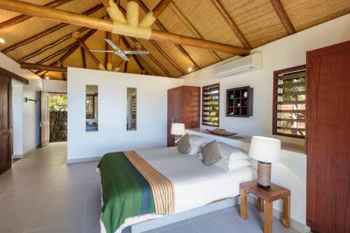 a bedroom with a white bed and a wooden ceiling at Eratap Beach Resort in Port Vila
