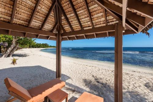 a beach with a chair and an umbrella and the ocean at Eratap Beach Resort in Port Vila