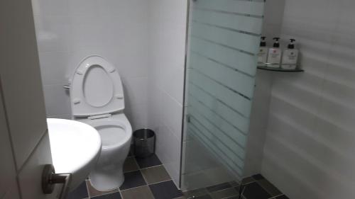 a bathroom with a toilet with a glass shower stall at Calli Hostel in Busan