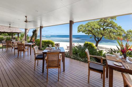 a restaurant with tables and chairs and the beach at Eratap Beach Resort in Port Vila