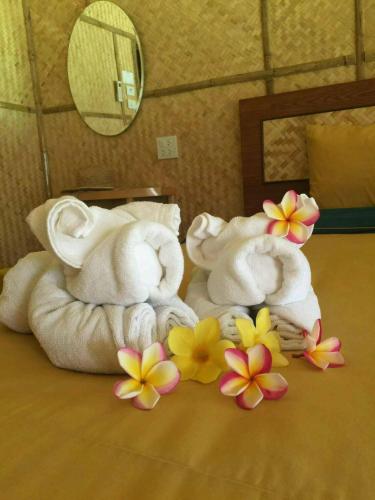 a group of towels and flowers on a bed at Bamboo House Resort in Kanchanaburi City