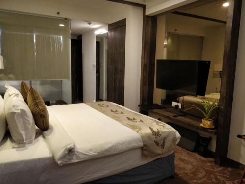 a bedroom with a large bed and a flat screen tv at Regenta Central Hotel & Convention Centre Nagpur in Nagpur