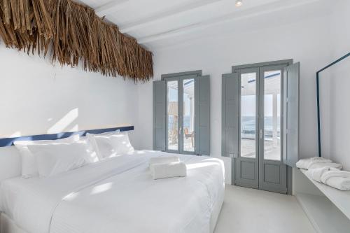 a white bedroom with a large white bed and windows at Sealine Villas in Tourlos