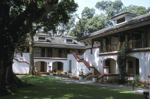 a large white building with a tree in the yard at Gokarna Forest Resort Pvt Ltd in Kathmandu