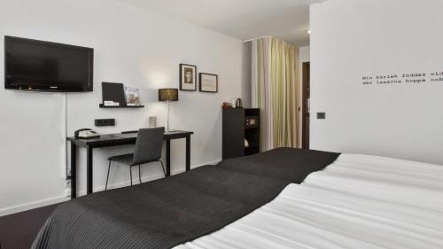 a bedroom with a bed and a desk and a television at Best Western Plus Grand Hotel Elektra in Ludvika
