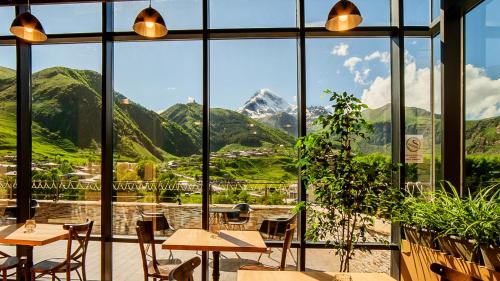 a restaurant with a view of mountains through windows at Porta Caucasia Kazbegi in Kazbegi