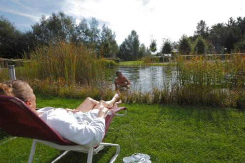 a woman sitting in a chair next to a lake at Curhaus Bad Kreuzen in Bad Kreuzen