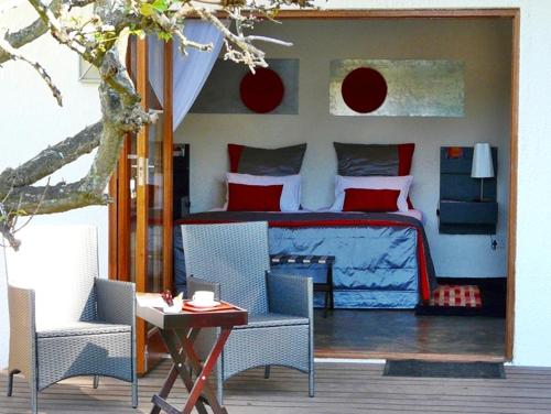 a bedroom with a bed and a table and chairs at KaapsePracht Bed & Breakfast in Somerset West