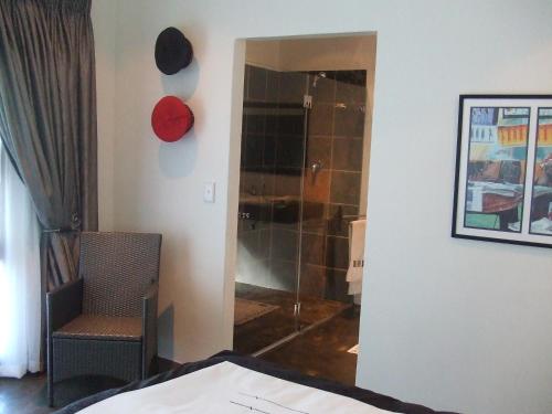 - une chambre avec une douche et une chaise dans l'établissement KaapsePracht Bed & Breakfast, à Somerset West