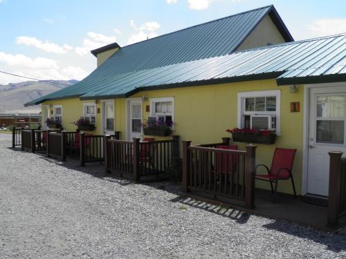 a yellow house with red chairs in front of it at Yellowstone Riverside Cottages in Gardiner