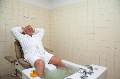 a man sitting in a bath tub in a bathroom at Viiking Spa Hotel in Pärnu