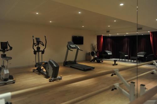 a gym with treadmills and exercise equipment in a room at Mercure Maurepas Saint Quentin in Maurepas