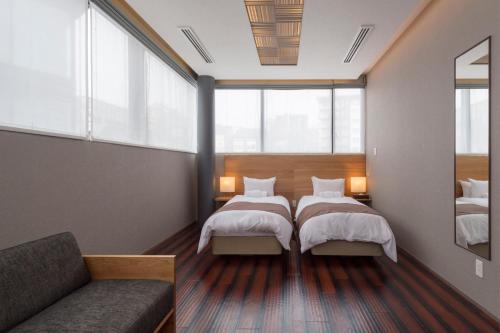 two beds in a room with a couch and windows at AYA Villa in Kutchan
