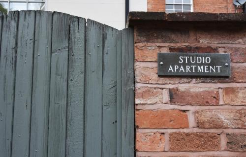 a sign on a brick wall next to a wooden fence at Dale Street Apartments Suite in Leamington Spa