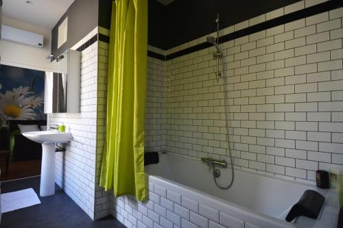 uma casa de banho com uma cortina de chuveiro amarela e uma banheira em Le Manoir em Souillac