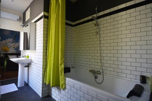 La salle de bains est pourvue d'une baignoire et d'un rideau de douche jaune. dans l'établissement Le Manoir, à Souillac