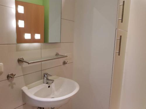 a white bathroom with a sink and a mirror at Am Maiglöckchenberg 19 in Ostseebad Karlshagen