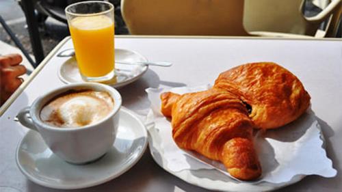 a table with a plate of croissants and a cup of orange juice at White House in Trani