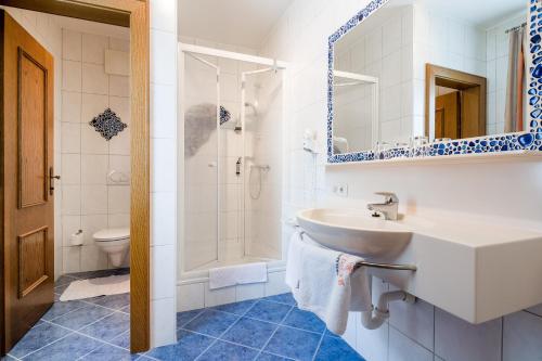ein weißes Bad mit einem Waschbecken und einer Dusche in der Unterkunft Gasthof Gierlinger in Obermühl