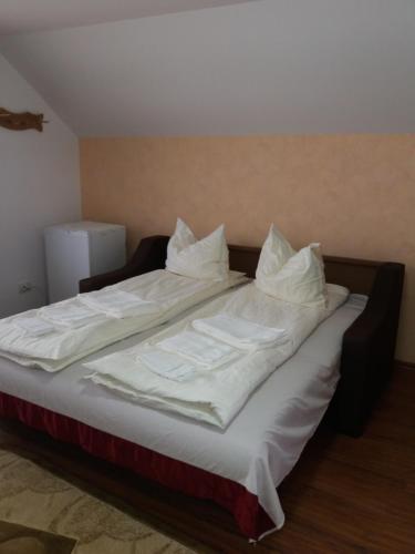 a large bed with white sheets and pillows on it at Casa Vlasea Albesti Sighișoara in Sighişoara