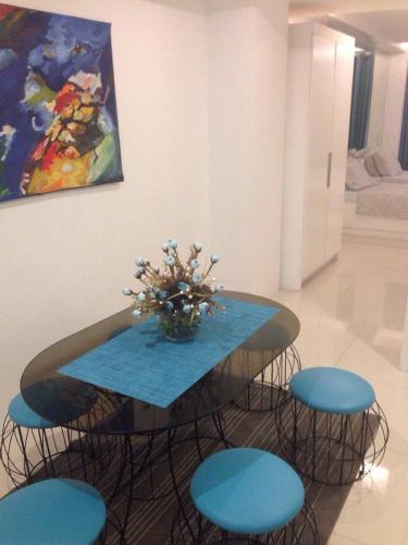 a table with blue chairs and a vase of flowers at Alta Residences in Daraga