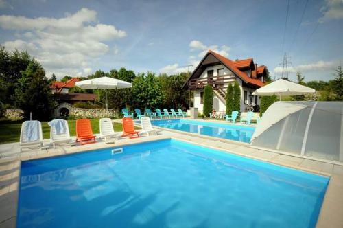 uma piscina com cadeiras e guarda-sóis em Pokoje Irys em Kazimierz Dolny