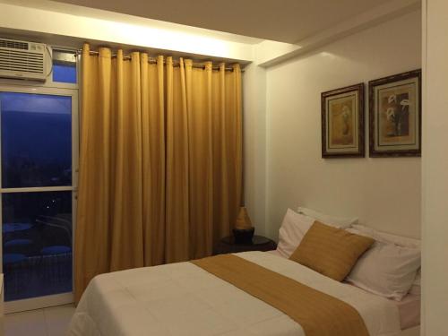 a bedroom with a large bed and a window at Alta Residences in Daraga