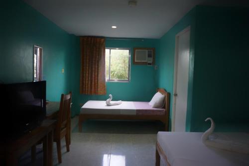 a green room with a bed and a window at Lylie Hotel in Cebu City